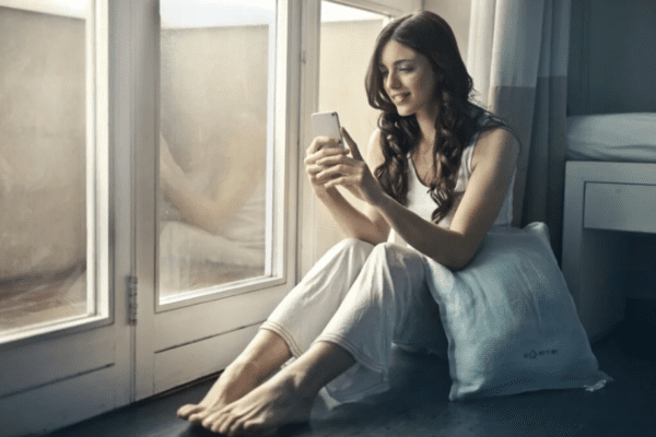 uzależnienie od telefonu, kobieta siedzi przy oknie z telefonem