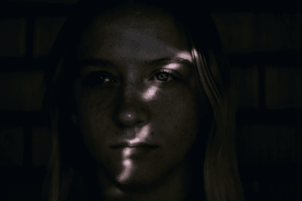 objawy depresji; zaciemniona twarz kobiety, przez nią przechodzi promyk swiatła