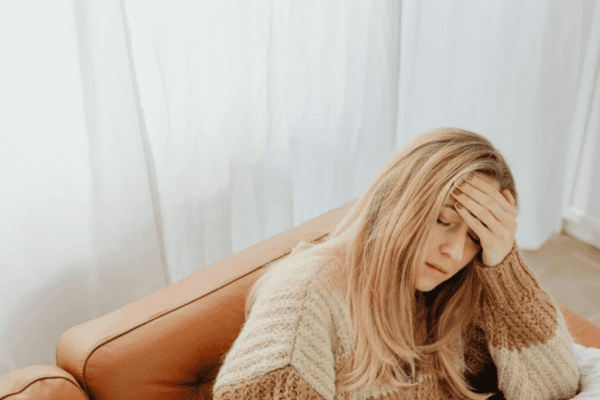 overthinking; kobieta siedzi trzymając dłoń na skroni