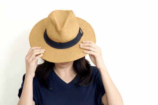 kobieta z kapeluszem na głowie, która ma cechy osoby nieśmiałe