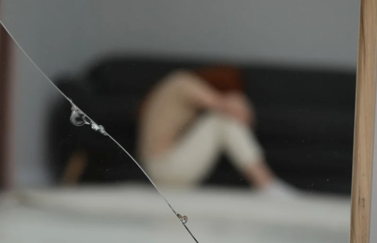 pęknięte lustro i kobieta która zmaga się z choroba afektywna depresja dwubiegunowa i objawy manii