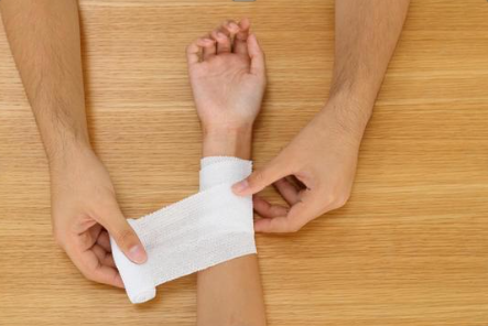 samookaleczanie, ktoś opatruje rękę młodej osobie