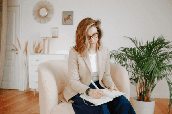 psycholog a psychoterapeuta, psychoterapeutka siedząca na fotelu pisząca notatki