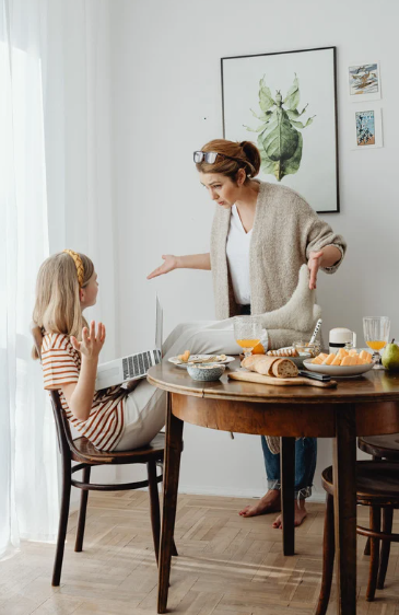 zaburzenia zachowania, Na zdjęciu widzimy młodą osobę siedzącą przy stole, która korzysta z laptopa, a obok niej znajduje się dorosła osoba, najprawdopodobniej matka, która gestykuluje i wygląda na zdenerwowaną. Ich interakcja może wskazywać na sytuację, w której pojawiają się pierwsze objawy problemów wychowawczych lub zaburzeń zachowania, gdzie dorosły stara się wyjaśnić, poprawić lub zrozumieć reakcję młodzieży. Tego typu interakcje mogą być częścią prawidłowego procesu socjalizacji, jednak w przypadku zaburzeń zachowania takie sceny mogą być również sygnałem trudności w adaptacji do norm społecznych i emocjonalnych. Psycholog mógłby wskazać na zachowania, które są połowę mniejsze niż oczekiwane w danym wieku, co może sugerować problemy w rozwoju.