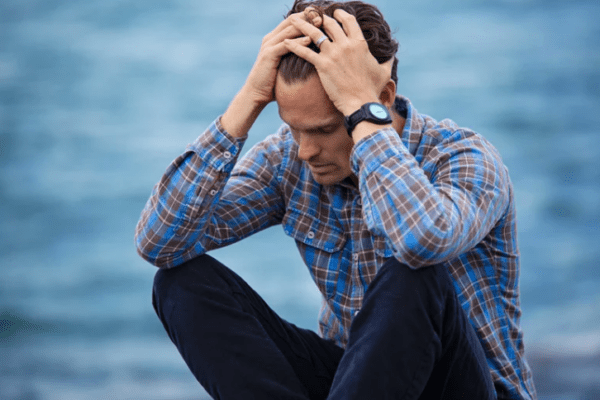 depresja agitowana, mężczyzna siedzący i trzymający się za głowę