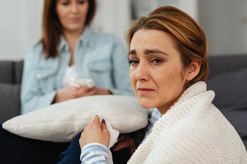 nadmierna skłonność do płaczu, kobieta siedzi zapłakana, trzema poduszkę w ręku