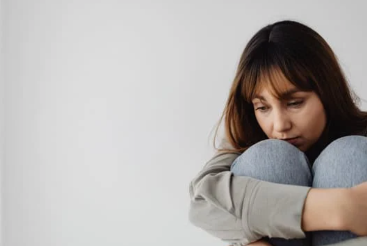 nietypowe objawy depresji, skulona siedząca kobieta 
