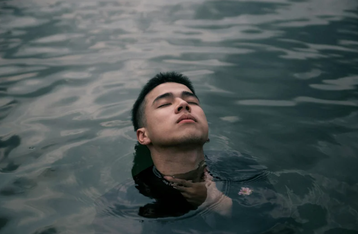 brak uczuć, mężczyzna zanurza się w wodzie, jego wyraz twarzy nie pokazuje uczuć