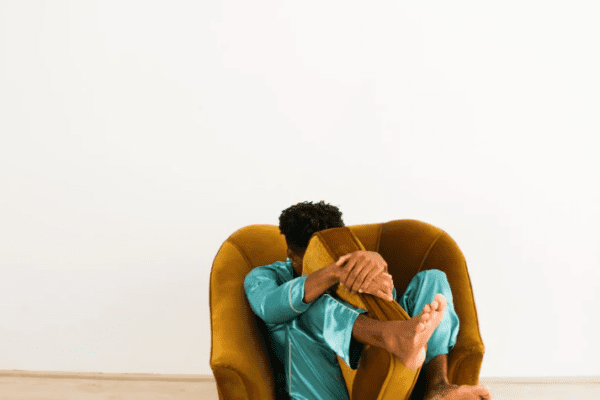 lęk a strach; Na zdjęciu widać osobę skuloną w fotelu, obejmującą nogi, co może symbolizować zaburzenia psychiczne oraz silne uczucia przytłoczenia. Taka postawa bywa kojarzona z lękiem uogólnionym, w którym lękiem i lęki pojawiają się nawet bez realnego zagrożenia, choć są przeżywane jako realnym zagrożeniem. Obraz sugeruje napięcie, poczucie zagrożenia oraz różne dolegliwości emocjonalne; można odnieść wrażenie, że osoba cierpi i zmaga się ze stanami podobnymi do depresji.