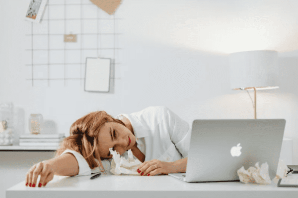 zmęczenie psychiczne; kobieta leży na biurku przed laptopem, wydaje się być bardzo zmęczona