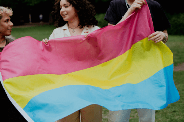 panseksualizm, kobiety i mężczyźni trzymający flagę panseksualizmu