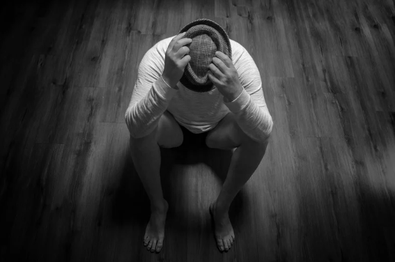brak chęci do życia; mężczyzna siedzi skulony na podłodze i patrzy w dół