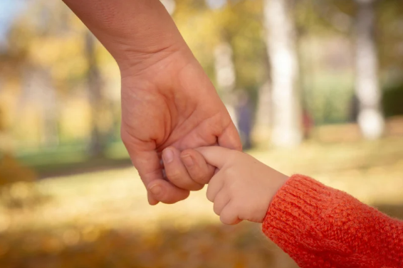 dkryj swoje wewnętrzne dziecko; dłoń dorosłego człowieka trzyma dłoń dziecka