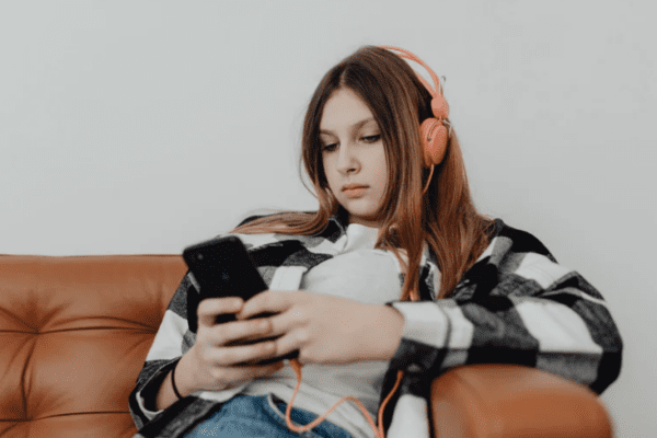jak rozmawiać z nastolatkiem, nastolatka słuchająca muzyki i grająca na telefonie