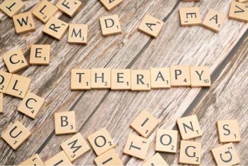 kiedy warto iść do terapeuty - na drewnie ułożony jest napis therapy