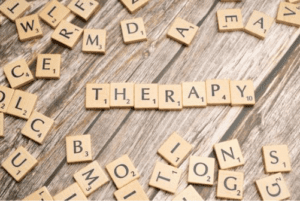 kiedy warto iść do terapeuty - na drewnie ułożony jest napis therapy