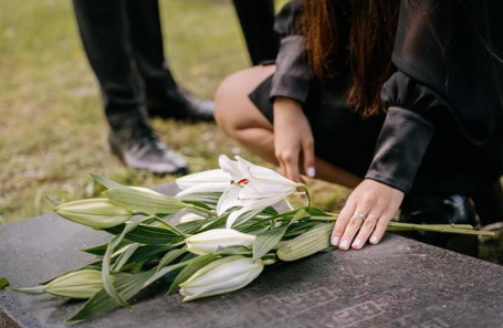 Psychoterapia po stracie bliskiej osoby — kiedy i jak szukać pomocy - kobieta składka białe kwiaty na nagrobek