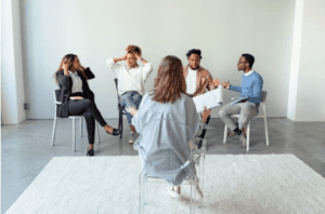 Psychoterapia indywidualna vs grupowa — co wybrać? - zdjęcie przedstawia 4 osoby na spotkaniu grupowym u psychoterapeuty