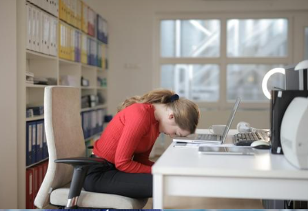 brak serotoniny objawy - zdjęcie przedstawia kobietę, której głowa ze zmęczenia spoczywa na laptopie