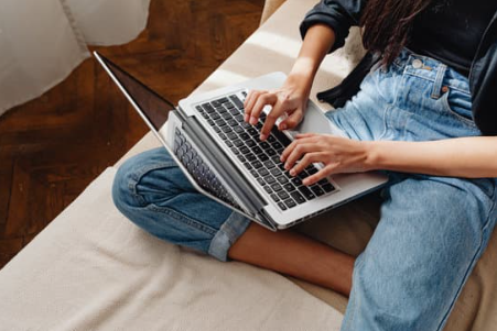 6 konsekwencji uzależnienia od internetu - zdjęcie przedstawia kolana kobiety na których spoczywa laptop