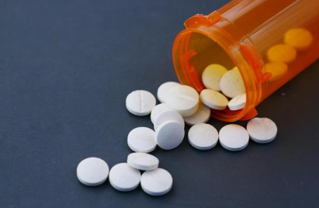 Czy antydepresanty to psychotropy? Wyjaśniamy różnice i podobieństwa - na zdjęciu przedstawiony jest pomarańczowy pojemnik na leki, z którego wysypują się tabletki