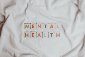 osoba chora psychicznie objawy - zdjęcie przedstawia napis 'mental health' ułożony z scrubble na białym prześcieradle