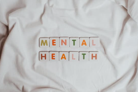 osoba chora psychicznie objawy - zdjęcie przedstawia napis 'mental health' ułożony z scrubble na białym prześcieradle